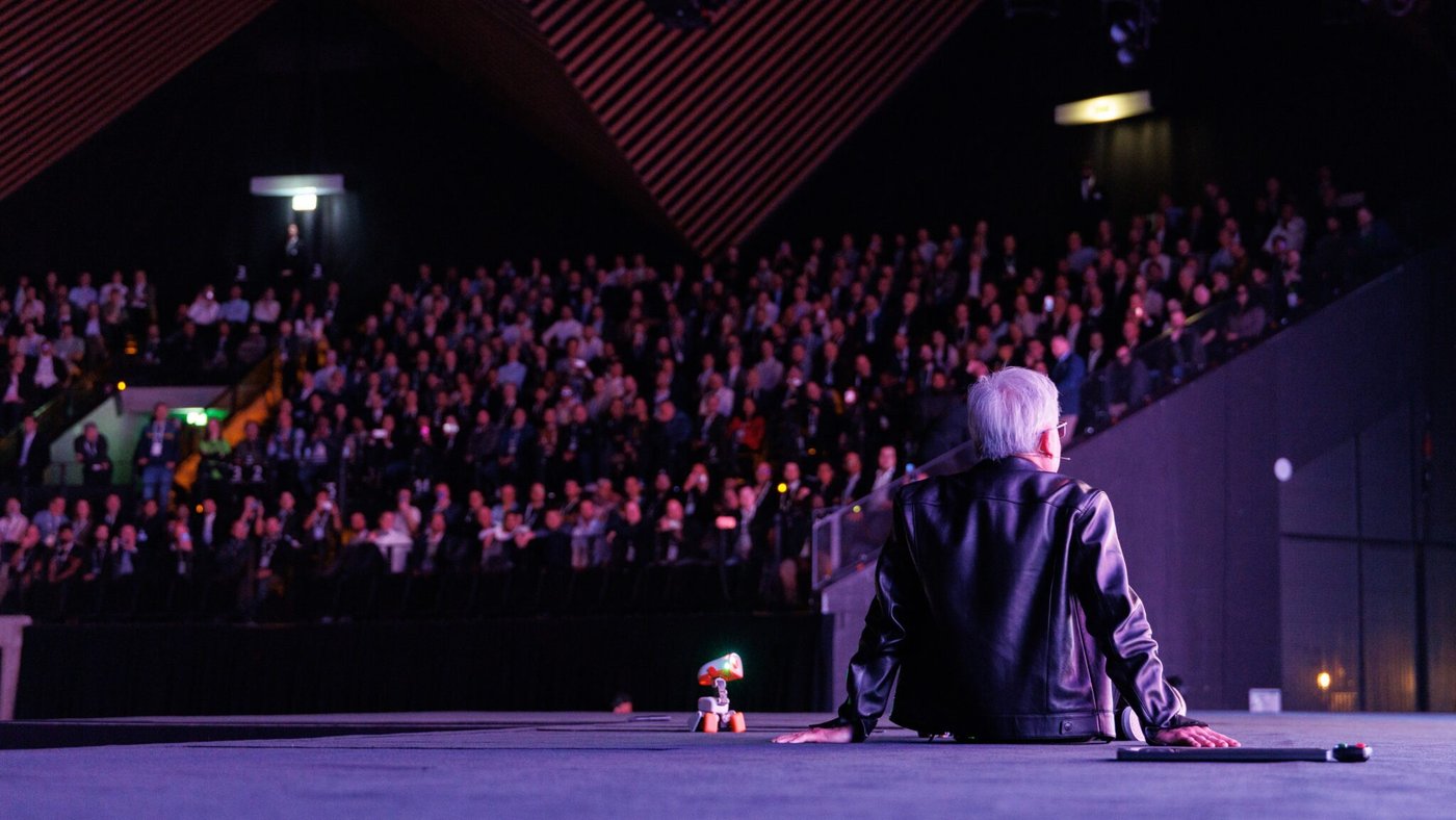 Jensen Huang, GTC Berlin 2026 keynote'u sırasında Tempodrom'da sahnede oturmuş, seyirciye bakıyor